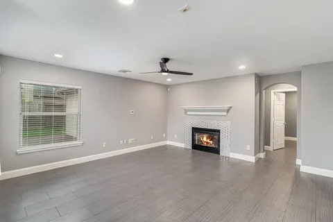 a view of an empty room with wooden floor fireplace and a window