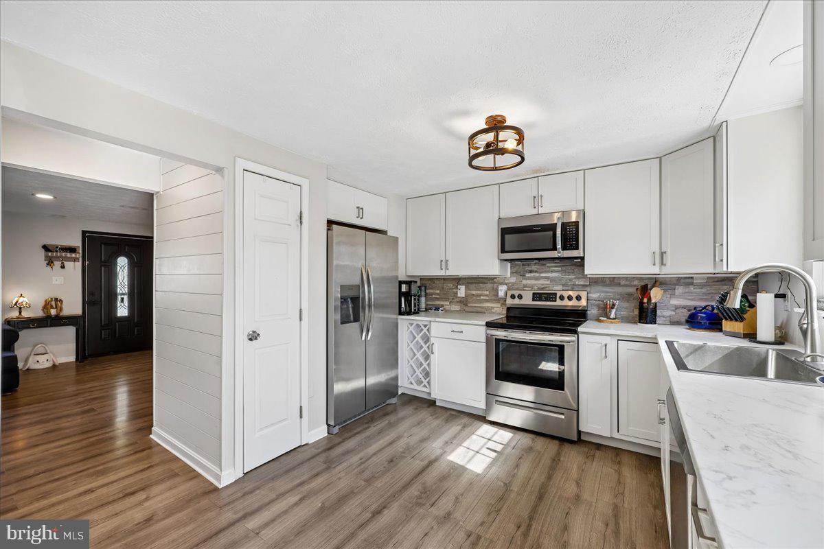 1476 Dockside Court Frederick, MD 21701 - Photo 12 of 34 a kitchen with stainless steel appliances a microwave a stove a sink dishwasher a refrigerator and white cabinets with wooden floor