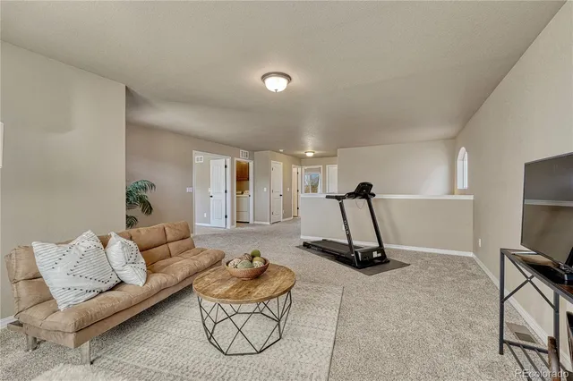 an empty room with chandelier fan and windows