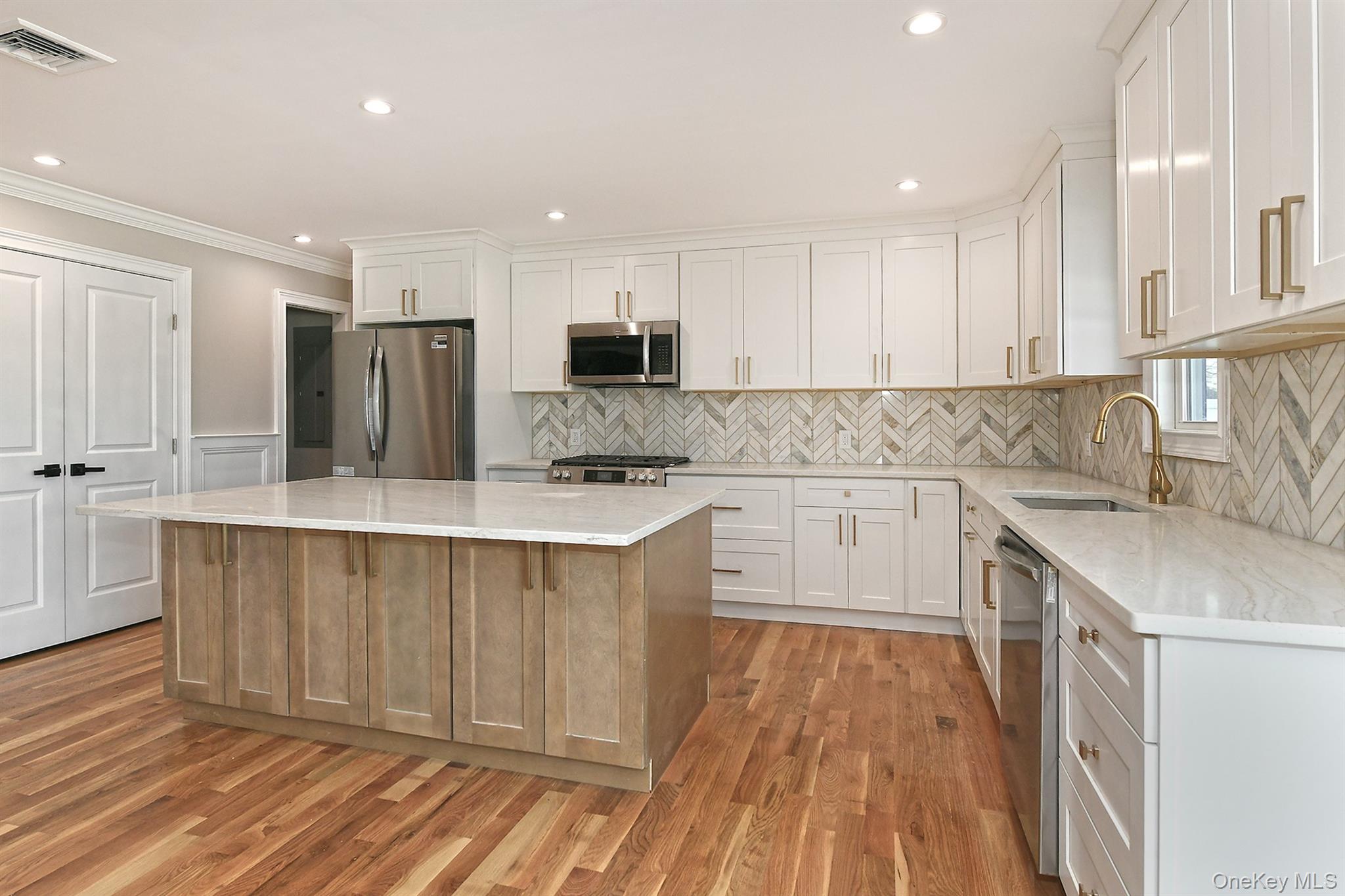 1903 George Court Merrick, NY 11566 - Photo 12 of 39 a kitchen with kitchen island white cabinets and stainless steel appliances