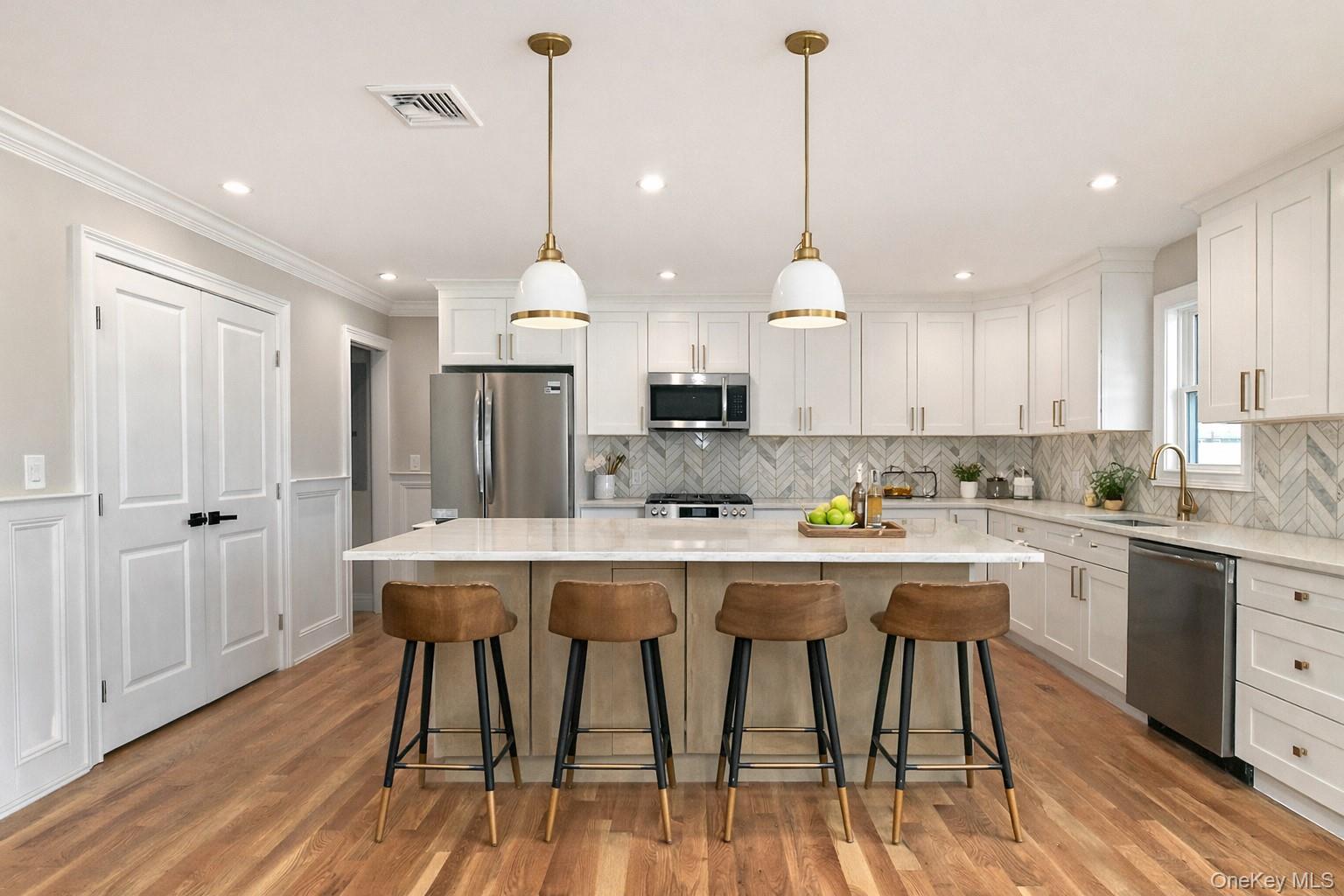 1903 George Court Merrick, NY 11566 - Photo 9 of 39 a kitchen with kitchen island a dining table chairs sink and cabinets