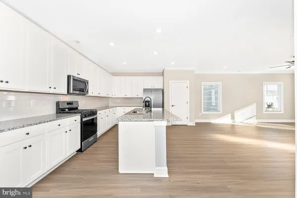a kitchen with stainless steel appliances granite countertop a stove top oven a sink dishwasher and a refrigerator with wooden floor
