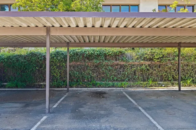 a view of a white house next to a yard with big trees
