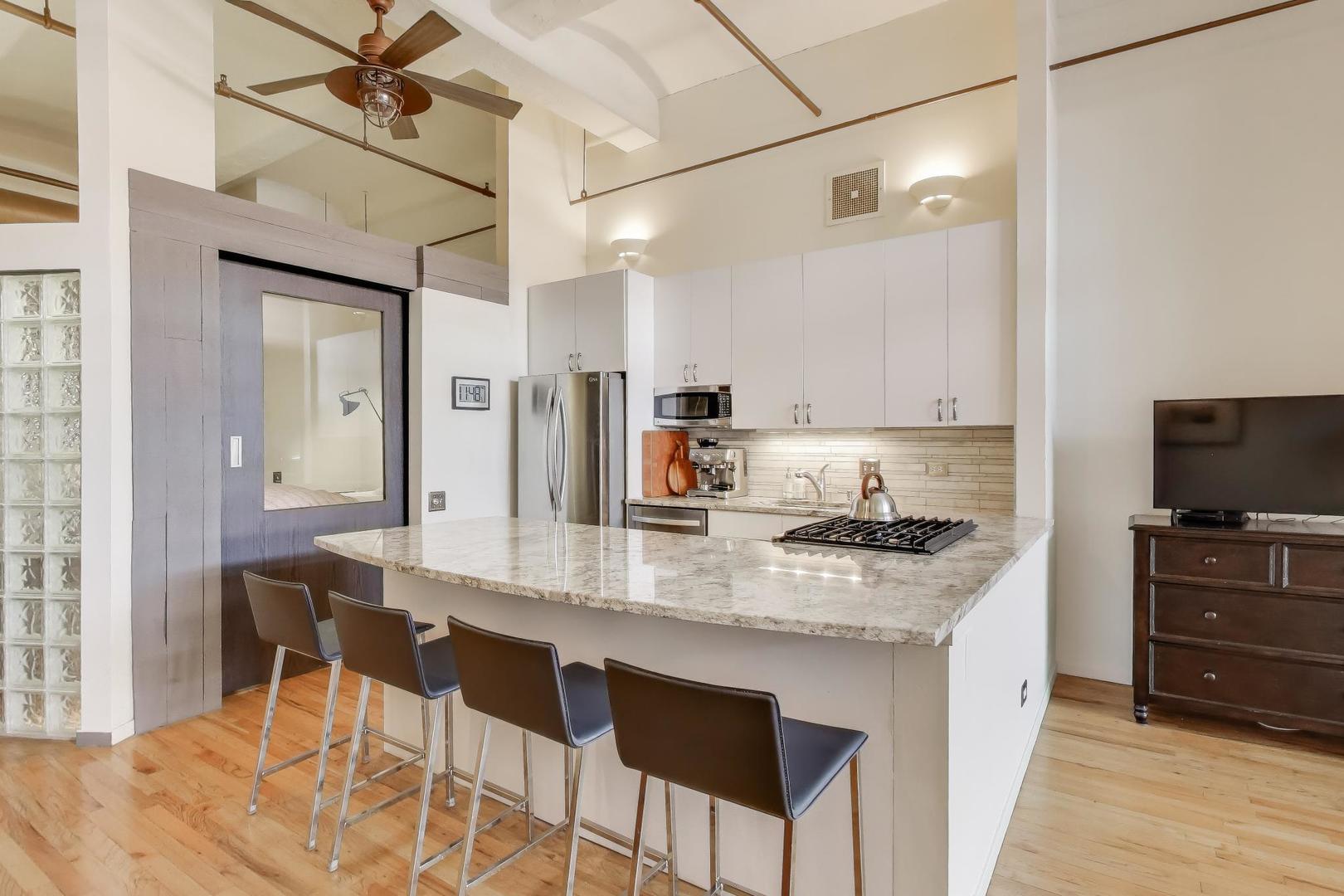 1000 West Washington Boulevard, Unit 418 Chicago, IL 60607 - Photo 11 of 20 a kitchen with stainless steel appliances granite countertop a sink a stove a dining table and chairs