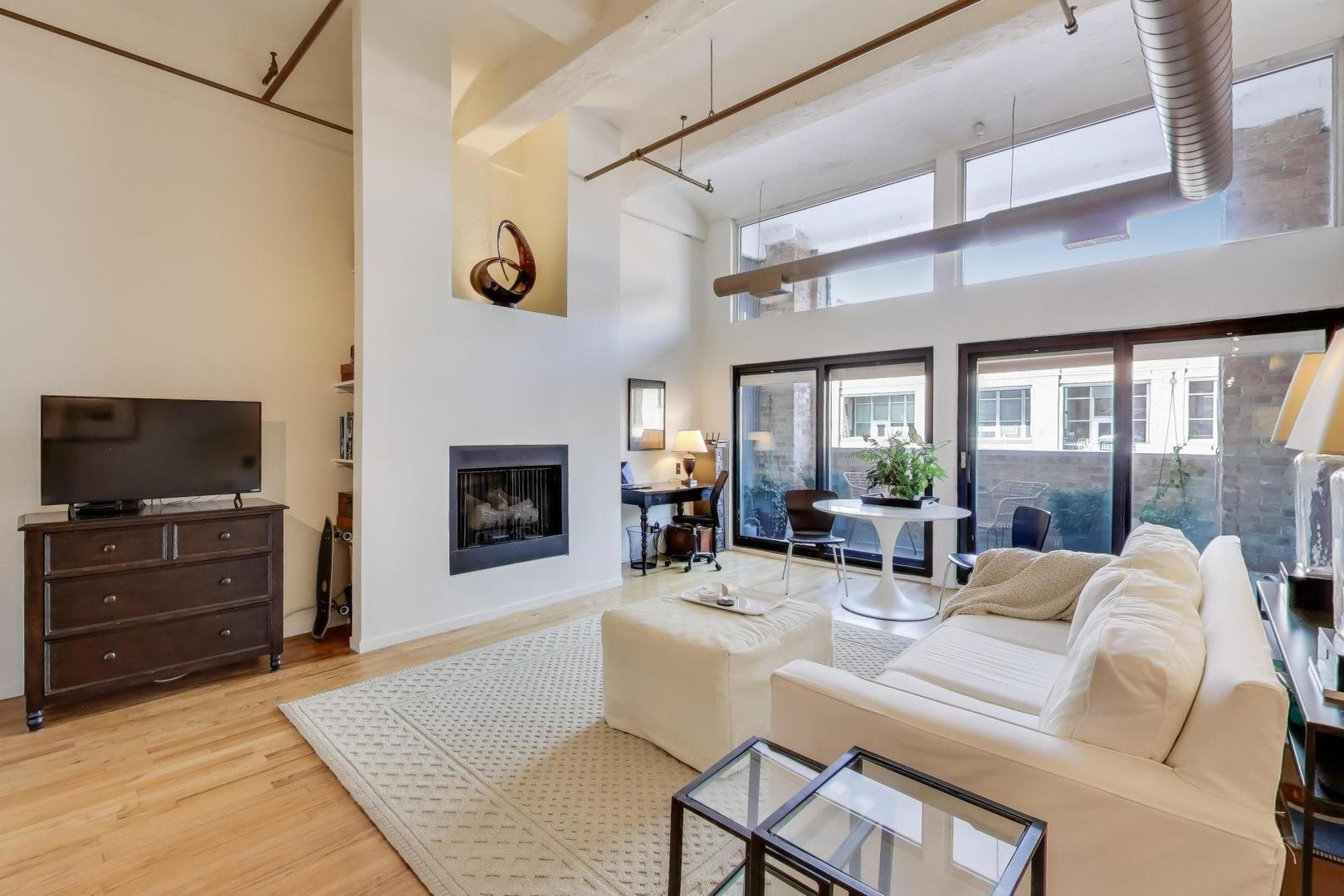 1000 West Washington Boulevard, Unit 418 Chicago, IL 60607 - Photo 6 of 20 a living room with furniture a flat screen tv and a fireplace