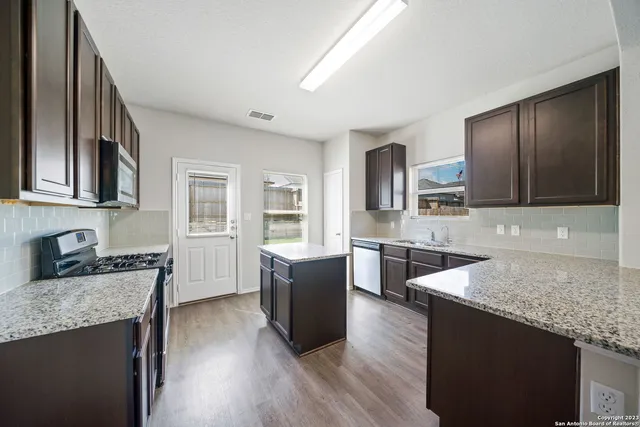 a large kitchen with granite countertop a large counter top space a sink stainless steel appliances and cabinets