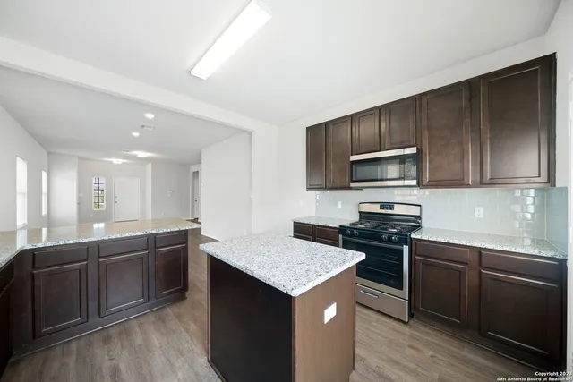 a kitchen with stainless steel appliances granite countertop a sink stove and microwave