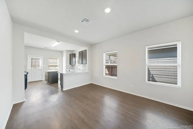 a view of a big room with wooden floor and windows