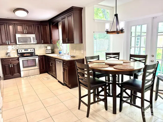 a kitchen with stainless steel appliances granite countertop a stove a sink dishwasher a dining table and chairs