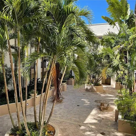 a view of multi story residential apartment building with a yard and potted plants