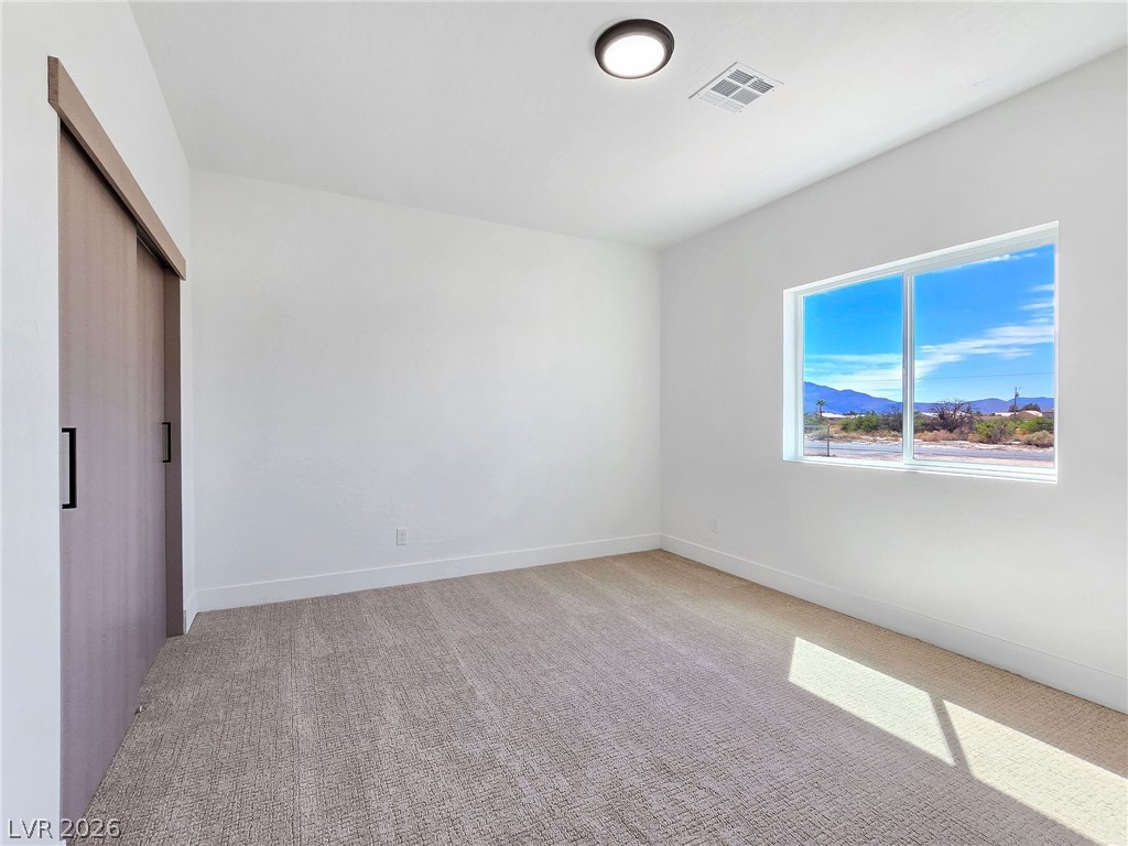 1120 West Gamebird Road Pahrump, NV 89048 - Photo 21 of 36 Unfurnished bedroom with light carpet, a closet, and a mountain view