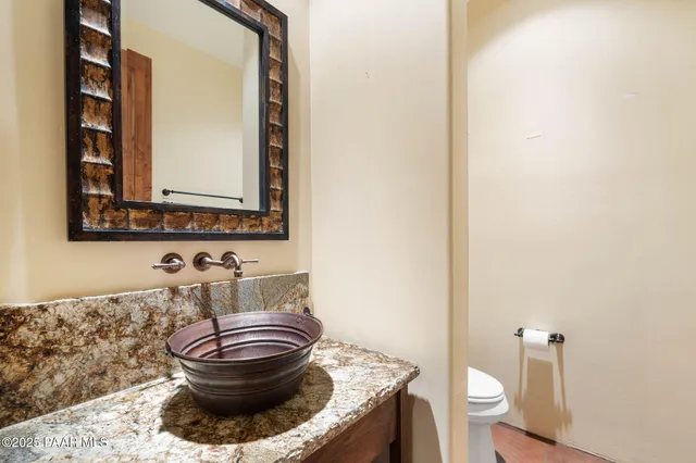 a bathroom with a granite countertop toilet and a mirror