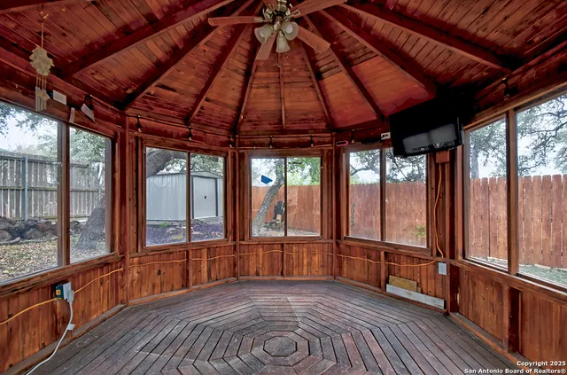 a view of an empty room with wooden floor and windows