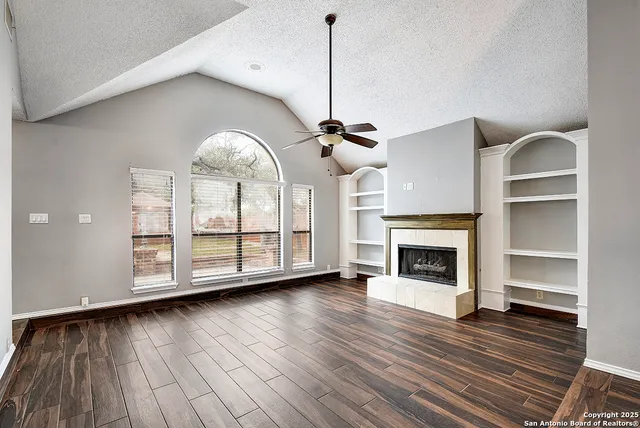 a view of an empty room with wooden floor fireplace and a window