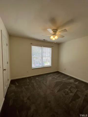 an empty room with a ceiling fan and window