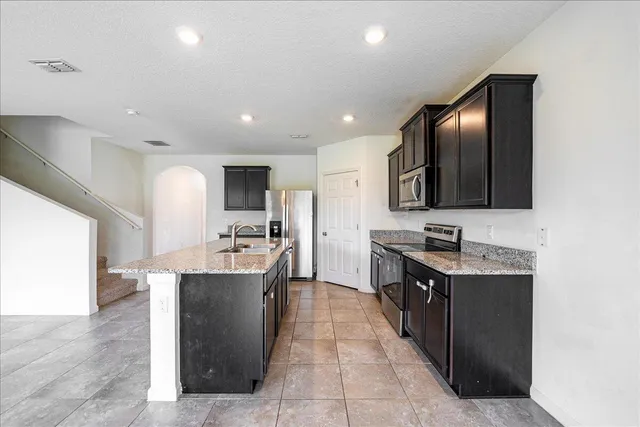 a large kitchen with a large counter top stainless steel appliances and cabinets