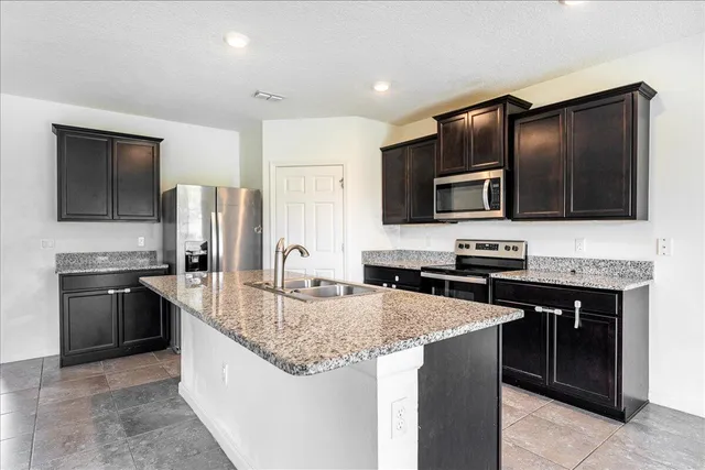 a kitchen with stainless steel appliances granite countertop a stove refrigerator sink and microwave
