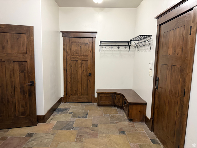 4536 North 475 East Provo, UT 84604 - Photo 27 of 65 Entryway featuring natural slate flooring, three panel wood doors with dark hardware, a built-in wood bench with storage, and decorative wall-mounted coat racks