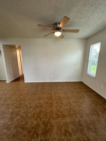 an empty room with windows and fan