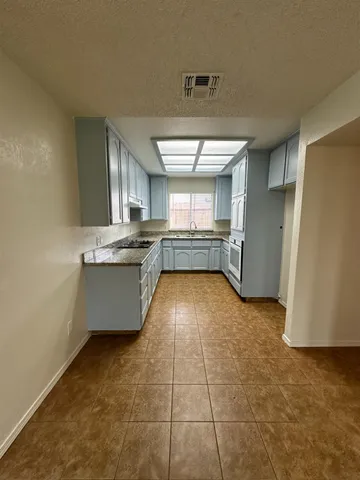 a view of kitchen with stainless steel appliances a stove a refrigerator a sink a microwave and cabinets