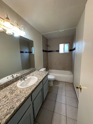a bathroom with a granite countertop sink a toilet and mirror