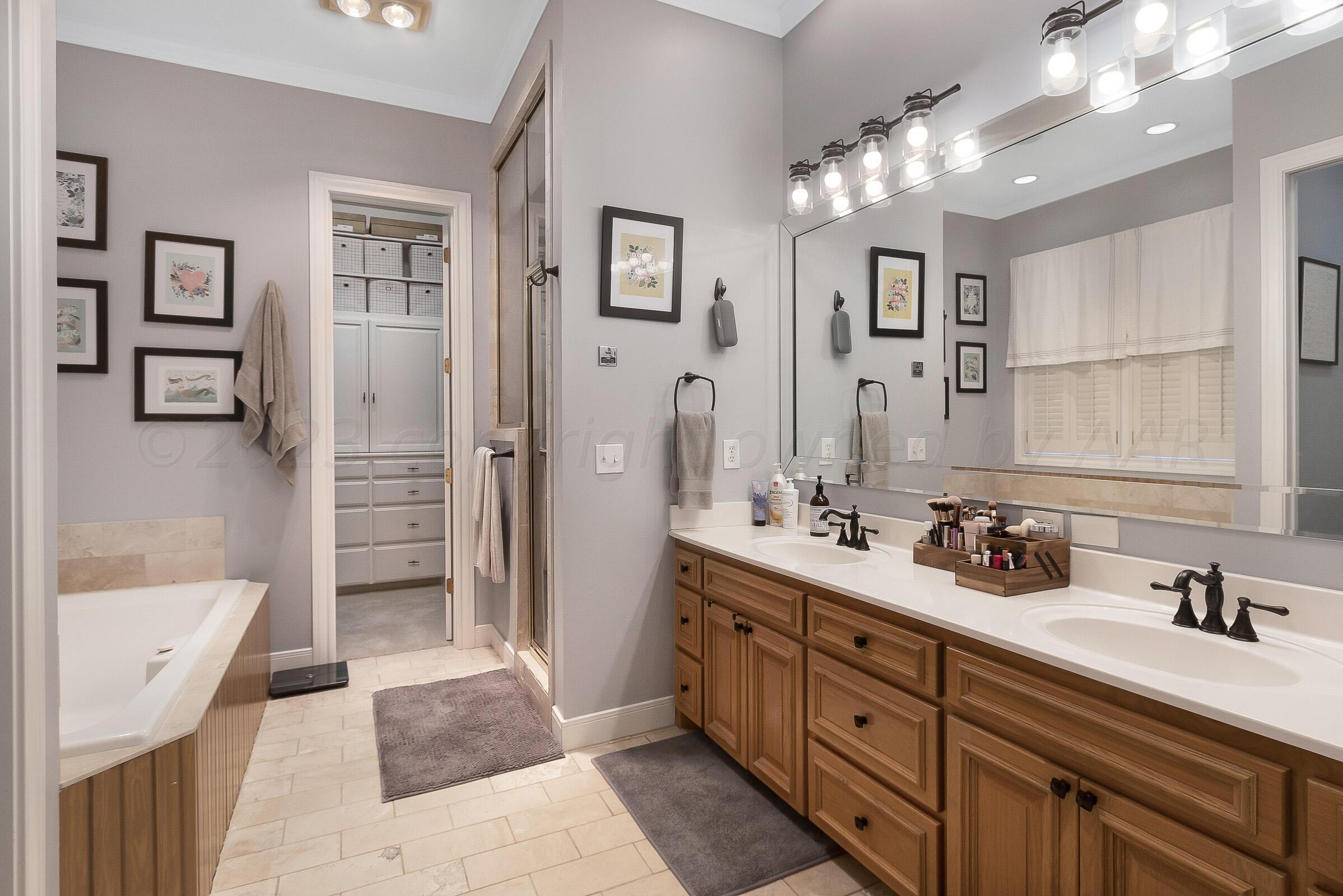 6202 Raintree Court Amarillo, TX 79119 - Photo 19 of 36 a spacious bathroom with a double vanity sink a large mirror a shower and bathtub