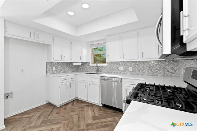 a kitchen with granite countertop a sink stove and cabinets