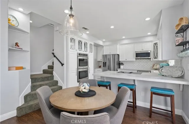 a kitchen with stainless steel appliances granite countertop a sink a stove a dining table and chairs
