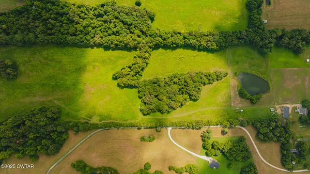an aerial view of a residential houses with outdoor space lake and trees all around