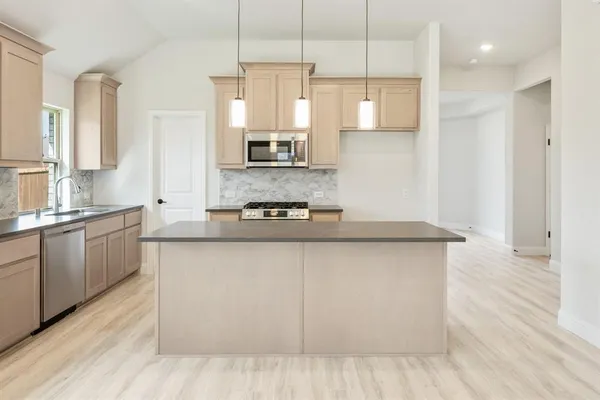 a large kitchen with granite countertop a sink a counter space appliances and cabinets