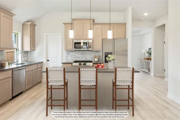 a kitchen with stainless steel appliances kitchen island granite countertop a dining table chairs and sink