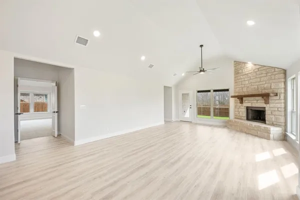 an empty room with wooden floor fireplace and windows