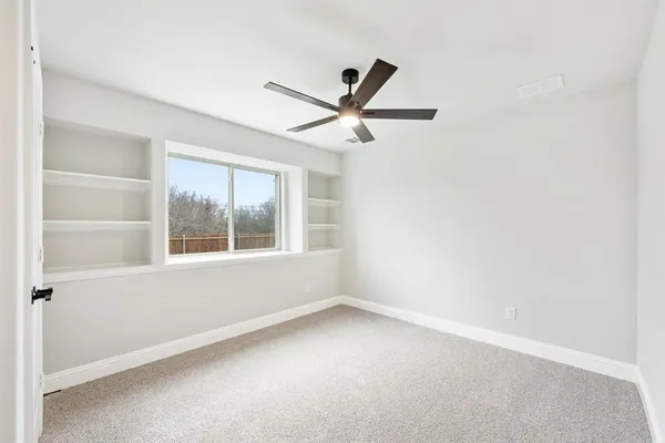 an empty room with a window and a fan