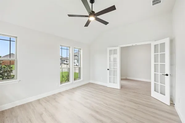 a view of an empty room with a window and wooden floor