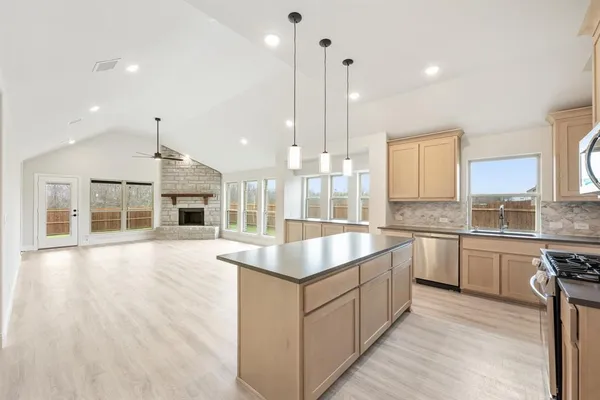 a kitchen with stainless steel appliances granite countertop a sink a stove and a wooden floors
