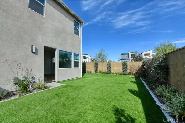 a view of a white house with a big yard and potted plants