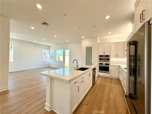 a large kitchen with stainless steel appliances granite countertop a lot of cabinets and wooden floor