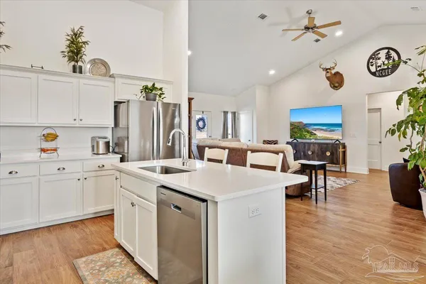 a kitchen with a sink dishwasher a stove a dining table and chairs with wooden floor