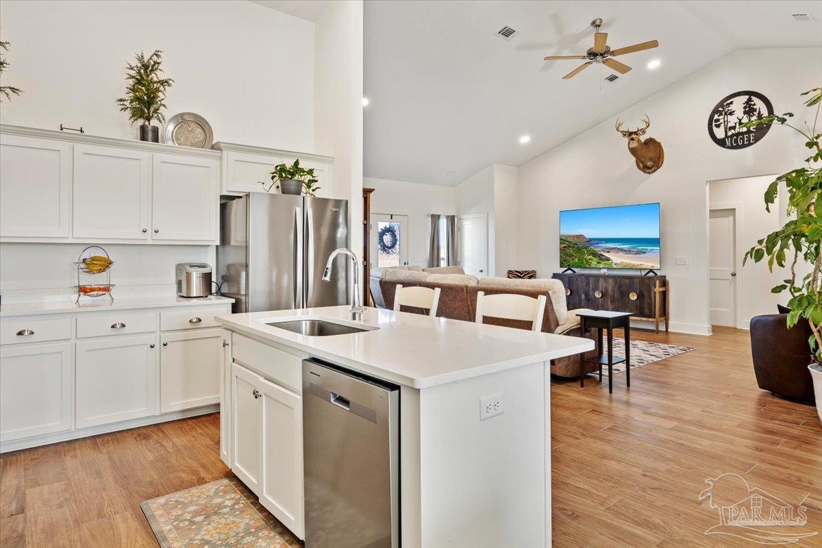 9303 Salter Road Pace, FL 32571 - Photo 7 of 23 a kitchen with a sink dishwasher a stove a dining table and chairs with wooden floor