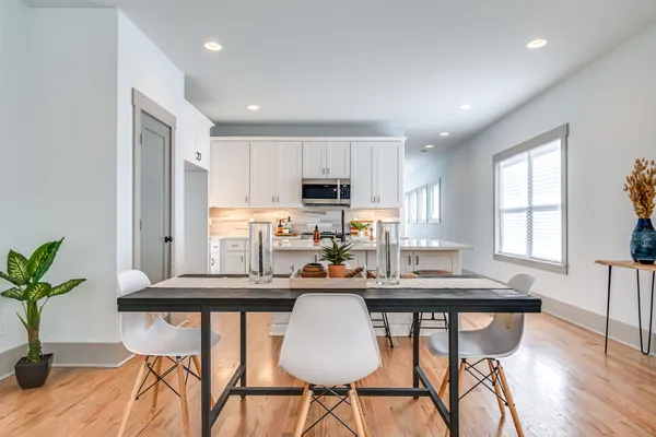 a kitchen with stainless steel appliances granite countertop a stove top oven a refrigerator a sink and white cabinets with wooden floor
