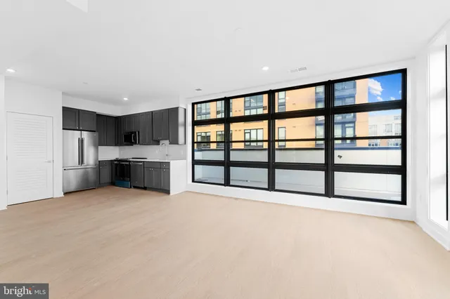 a large white room with kitchen island stainless steel appliances a large window and a large window