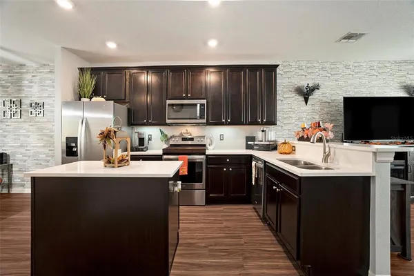 a kitchen with kitchen island a sink dishwasher stove and oven with wooden floor