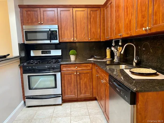a kitchen with granite countertop a stove top oven microwave and cabinets