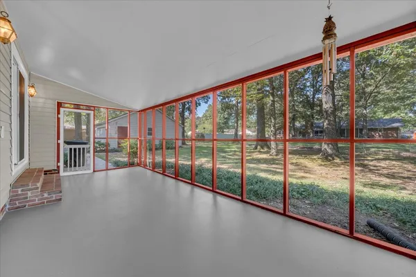 a view of an empty room with wooden floor and windows
