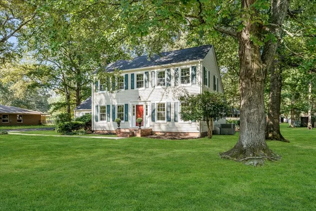 a front view of a house with a garden and trees