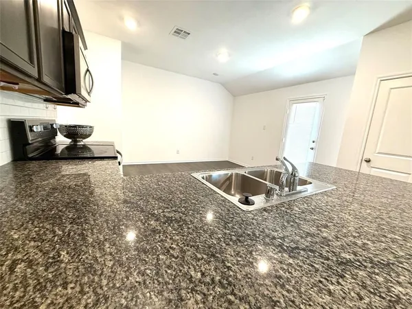 a kitchen with granite countertop a sink and a stove top oven