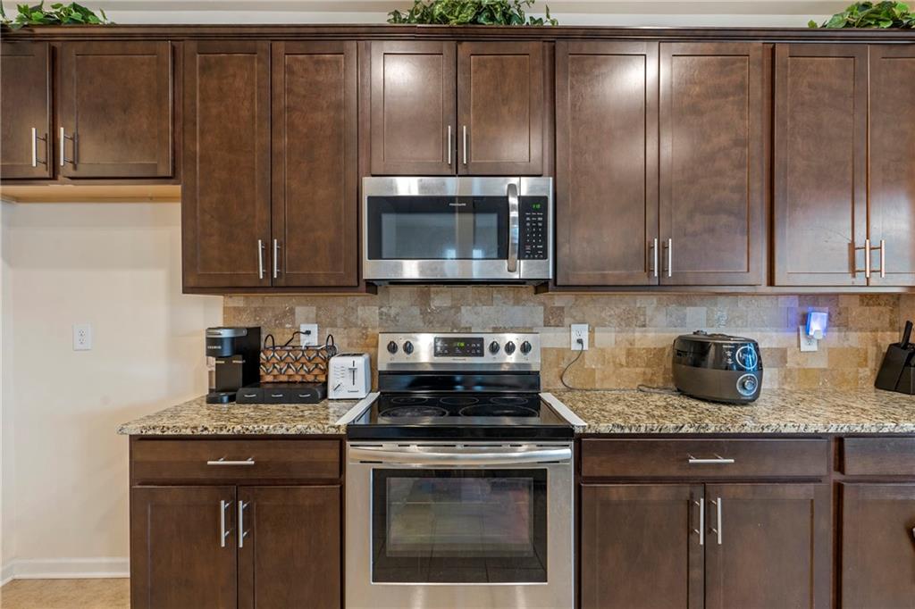 4265 Almanor Circle Norcross, GA 30071 - Photo 12 of 34 a kitchen with granite countertop a stove a microwave a sink and cabinetry