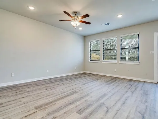 an empty room with wooden floor and windows