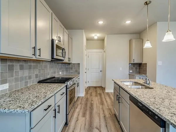 a kitchen with kitchen island granite countertop a sink a counter space appliances and cabinets