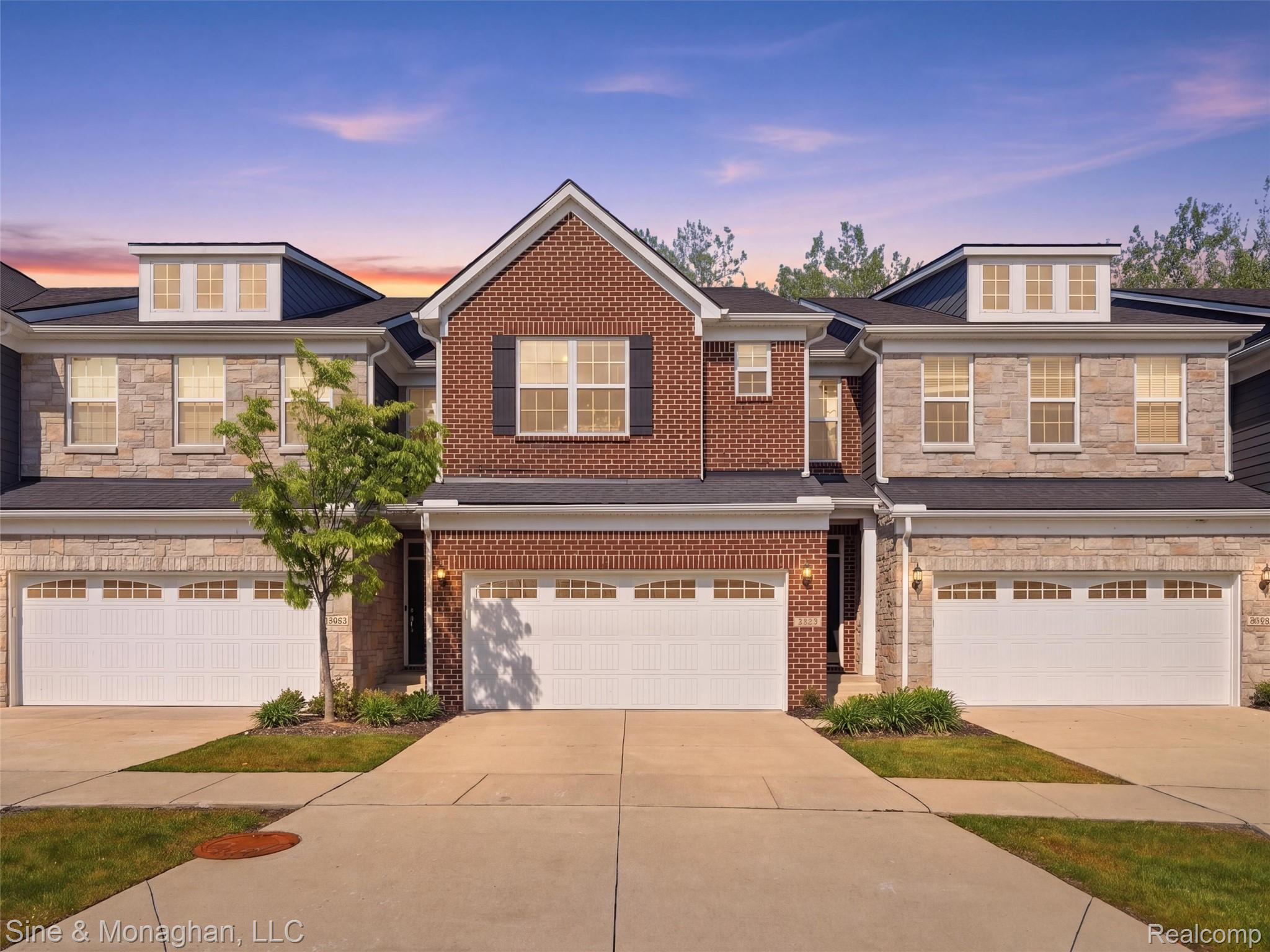 24827 Ivy Road Novi, MI 48375 - Photo 2 of 38 Townhouse exterior featuring a brick and stone facade, multiple dormer windows, and attached garages with panel doors